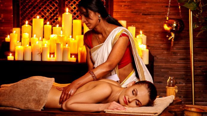 Young woman having oil Ayurveda spa treatment. Burning candle background.