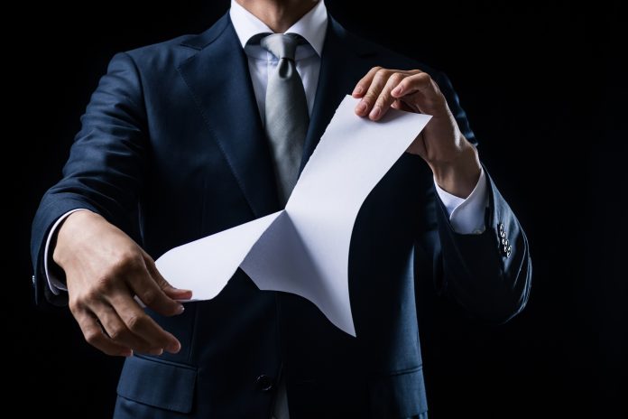 Businessman tearing white paper apart