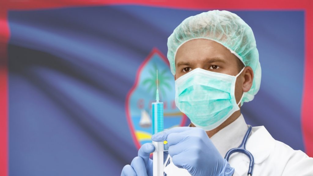 Doctor holding a syringe in front of Guam flag