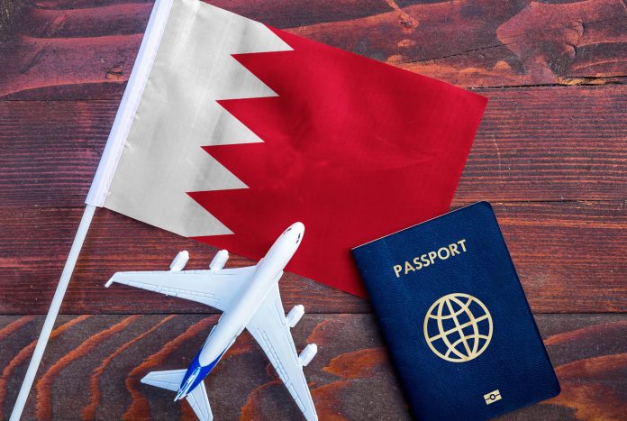 Flag of Bahrain with passport and toy airplane on wooden background.