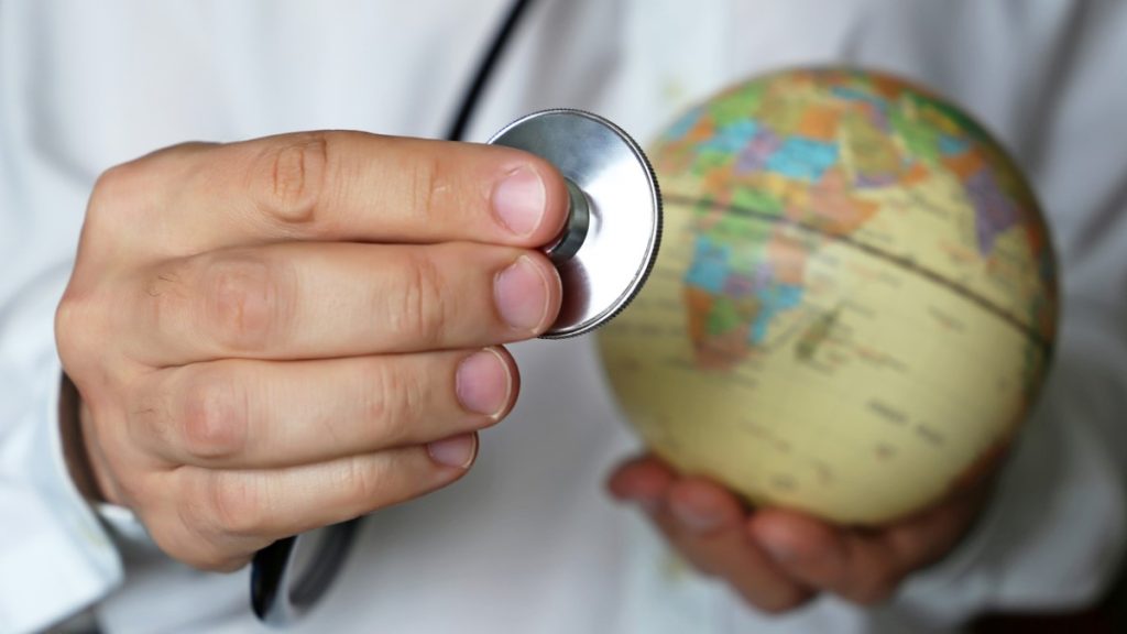 Doctor holding stethoscope next to a globe