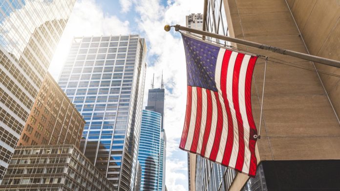 US flag with a skyscraper in the background