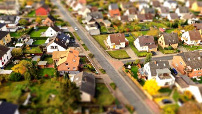 Suburb with family houses, front gardens and afterban, aerial view with tilt shift effect