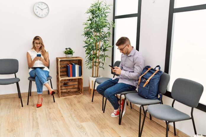 Two hispanic person smiling happy using smartphone at waiting center
