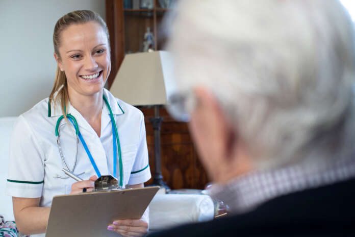 Nurse Taking Medical Notes From Senior Man At Home On Visit