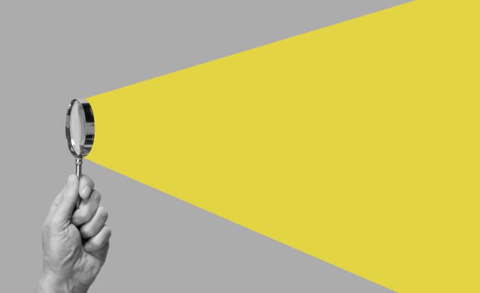 Man hand with magnifying glass. Yellow ray coming from loupe. Conducting check, information search and analysis concept. Spy, accountant, auditor job in abstract style.