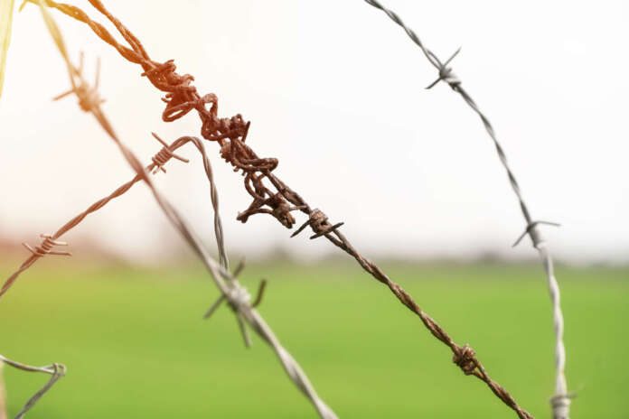 razor barbed wire and grass field border line control
