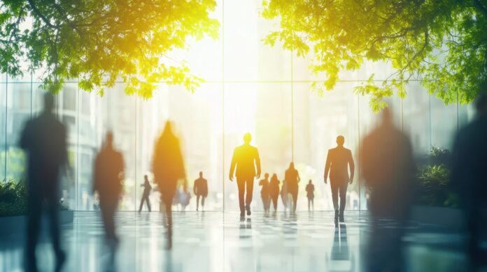 Silhouetted business professionals in sunlit office atrium