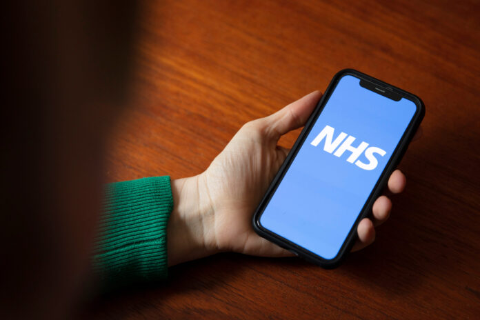 LONDON, UK - April 6th 2020: A person using the NHS healthcare smartphone app
