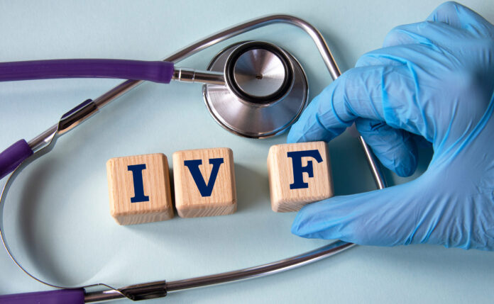 A hand in a medical glove puts cubes with the abbreviation IVF on the background of a stethoscope