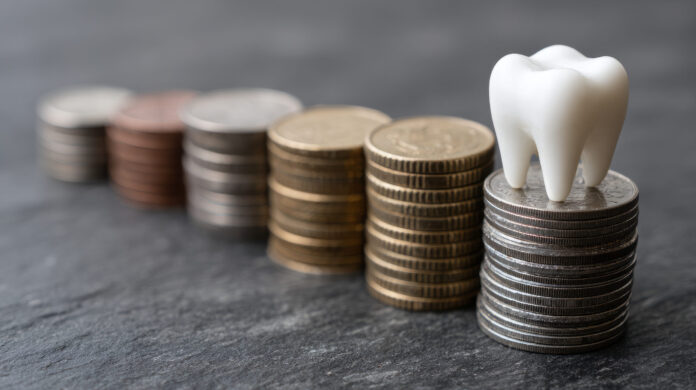 Dental cost concept with tooth on stacked coins