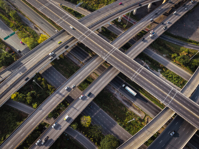 AdobeStock 1896215257 Aerial view city transport junction cross modern road morning light with vehicle movement