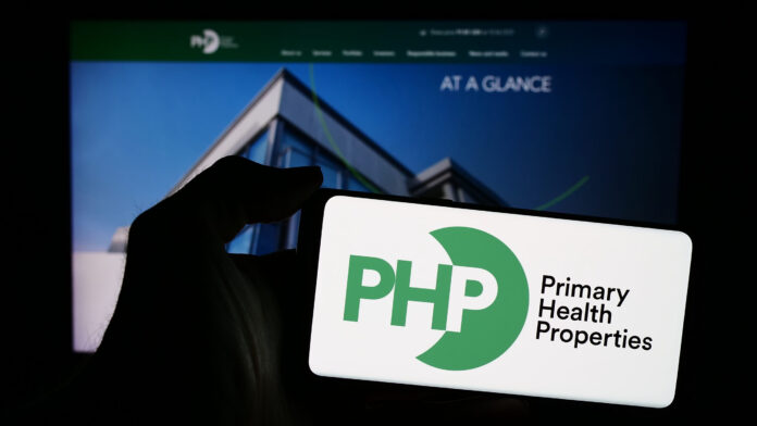 Stuttgart, Germany - 04-04-2024: Person holding smartphone with logo of British company Primary Health Properties plc (PHP) in front of website. Focus on phone display.